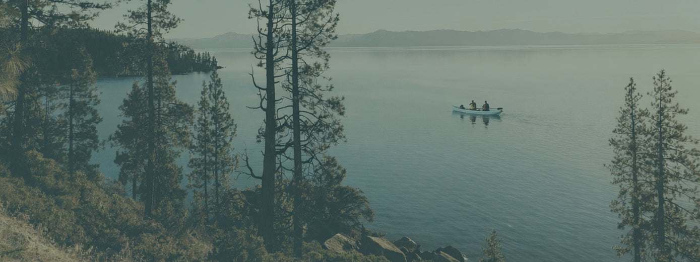 kayakers in the distance on a mountain lake at dusk