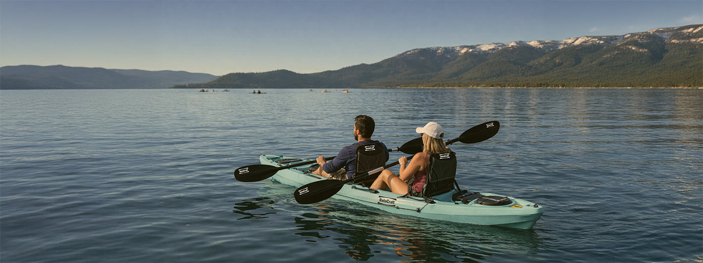 kayakers on a turquoise kayak paddling on a mountain lake on a sunny day